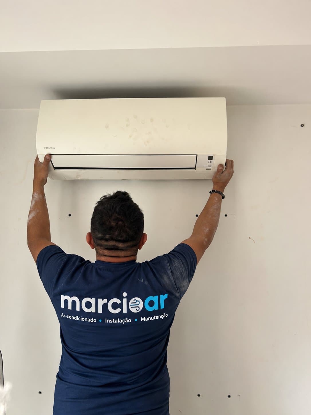 Técnico encaixando a unidade interna do ar-condicionado no suporte