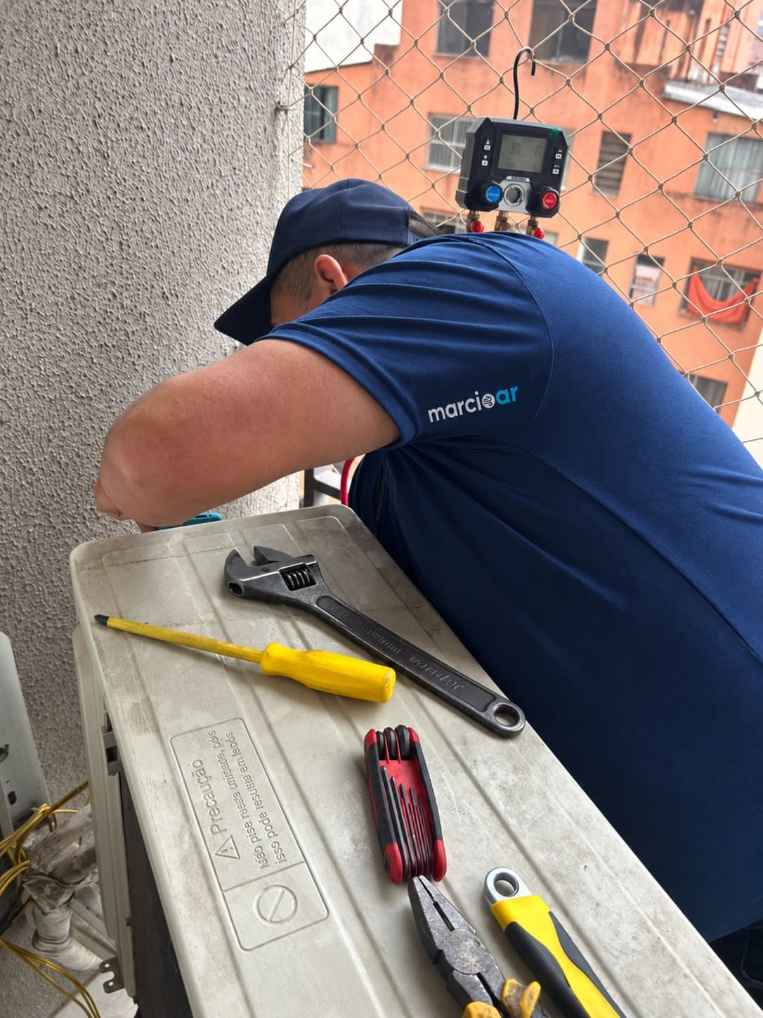 Técnico medindo a pressão do gás com manifold na condensadora da varanda